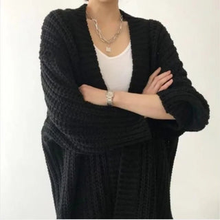 Manteau long noir en maille texturée, col châle, manches longues, devant ouvert.