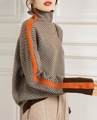 Blouse col montant à motif chevrons noir et blanc, passepoil orange, bord marron aux manches.