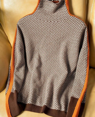Blouse à col montant motif chevrons noir et blanc, bordures orange et marron, sans manches apparentes.