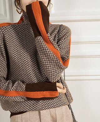 Détail col montant et manches de la blouse motif chevrons noir et blanc, bordures orange.