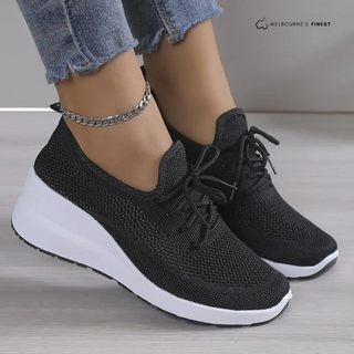 Baskets orthopédiques femme noires, vue 3/4, lacets noirs et semelle blanche.