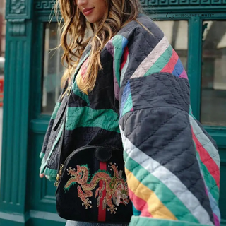 Manteau matelassé noir à rayures multicolores, coupe ample, manches longues.