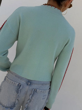 Cardigan bleu clair à boutons, motif pieuvres rouges visible au dos, manches longues.