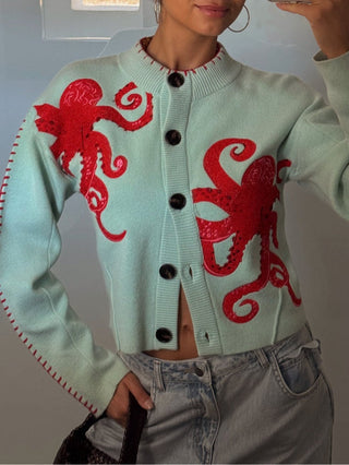 Cardigan bleu clair à motifs pieuvres rouges, fermeture boutonnée et encolure côtelée.