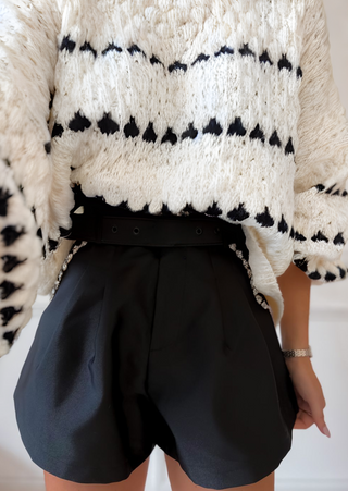 Pull en tricot vanille à motifs rayés noirs, gros point texturé et encolure ras du cou.