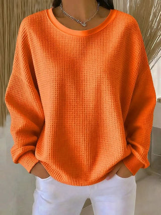 Pull en tricot orange à col rond, manches longues, poignets et ourlet côtelés.