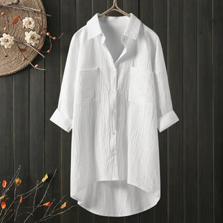 Chemise longue blanche à coupe ample, col chemise, boutons, poches poitrine.