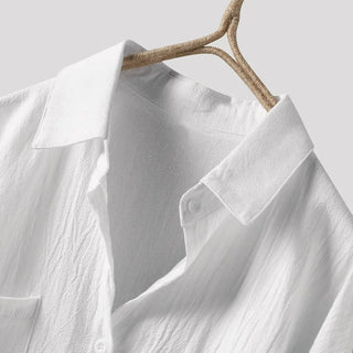 Chemise longue blanche, détail col et boutons ronds sur patte, tissu texturé.