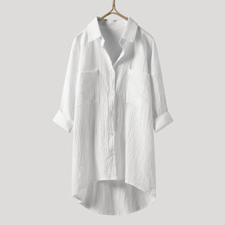Chemise longue blanche à coupe ample, col chemise, boutons, ourlet asymétrique.