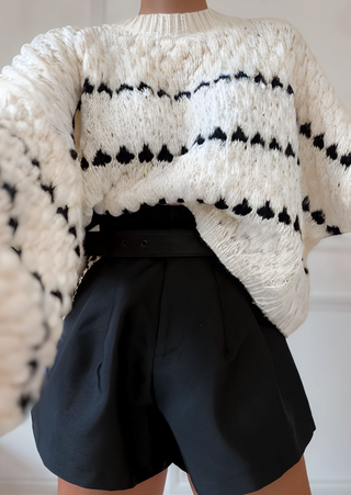 Pull en tricot vanille à rayures noires horizontales, encolure ras du cou, maille texturée.
