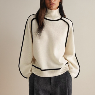 Pull col roulé en maille beige clair, bordure noire contrastée sur le col et les manches.