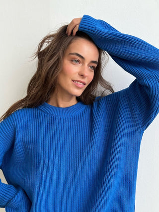 Pull en tricot bleu à encolure ronde côtelée, manches longues rabattues.