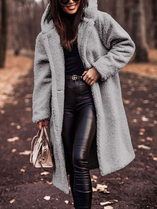 Manteau teddy long gris clair à capuche, fermeture boutonnée et texture duveteuse
