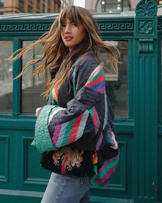 Manteau noir matelassé, motifs géométriques multicolores et bordure turquoise sur les manches