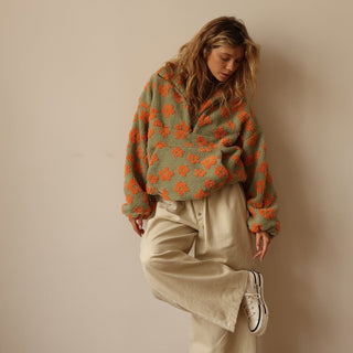 Pull quart de zip en polaire vert olive à fleurs orange, zip demi-hauteur au col.