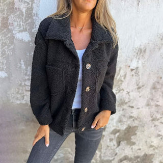 Manteau d’hiver noir en tissu bouclé, col chemise, boutons, poches plaquées.