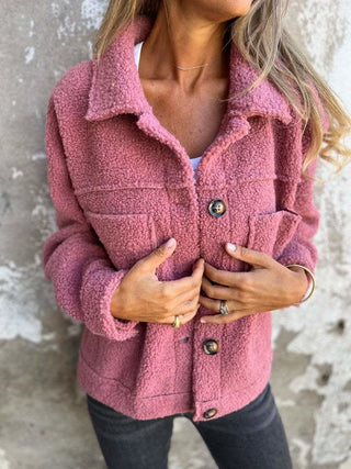 Manteau d’hiver rose en tissu bouclé, col chemise, boutons et poches plaquées.