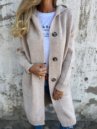 Manteau long en maille beige, fermeture boutonnée dorée, poches et col châle.
