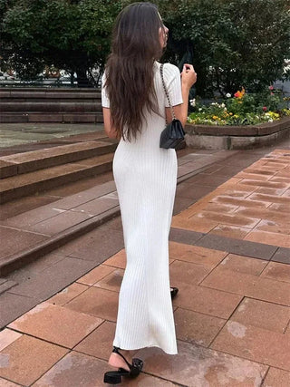Robe en maille blanche, dos et patte boutonnée, manches courtes, fente à l’ourlet.