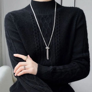 Pull col roulé noir en maille, motif torsadé discret sur le devant.