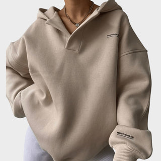 Sweat à capuche beige chic, col boutonné à demi-zip, manches longues, poignets côtelés.