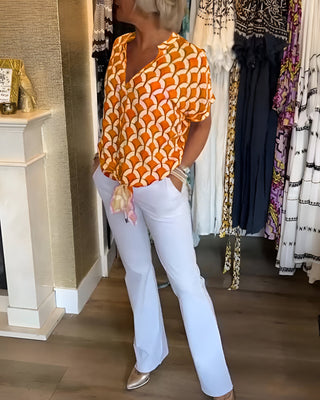 Chemisier décontracté à manches courtes, encolure V, motif géométrique orange et blanc.