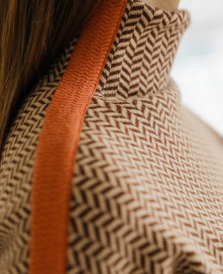 Gros plan tissu : motif chevrons noir et blanc, bande orange contrastante sur l’empiècement.