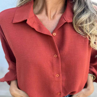 Blouse femme rouge à fermeture boutonnée, col chemise et gros plan sur la patte de boutons.